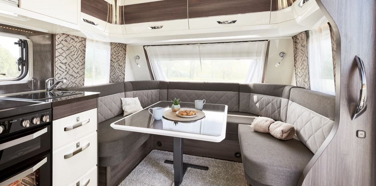 Moderner Wohnwagen-Innenraum mit Sitzecke, Tisch und Küchenbereich
